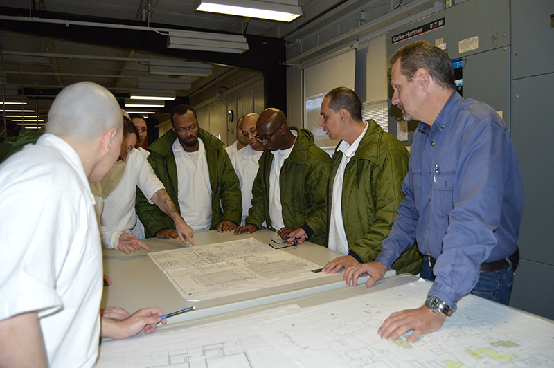 Photo of supervisor and offenders discussing a drawing of a map